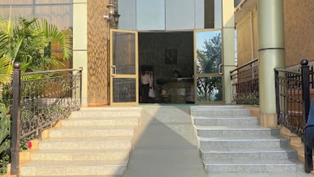 A building with a staircase leading to a glass door entrance. - Country Motel (Rubaare)