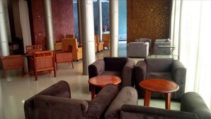 A lobby with seating arrangements including sofas and chairs, a coffee table, and a view through a large window. - Country Motel (Rubaare)