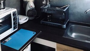 Una cocina moderna con armarios de madera, horno empotrado, tostadora, cafetera y escurreplatos.