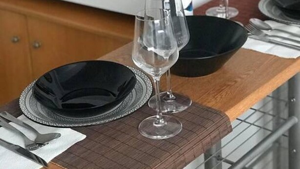 Una mesa de comedor preparada con platos, copas de vino y cubiertos.