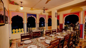 A dining area with a long table set for multiple guests, chairs, and a ceiling fan.
