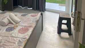 Camera da letto con un letto, un comodino, un armadio, una finestra con tende e vista su un giardino.