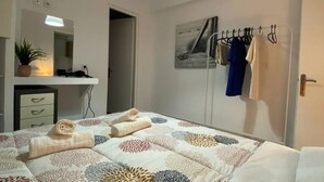 Una camera da letto con un letto, un comodino, uno specchio, uno stendino a parete e una porta.