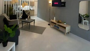 Un soggiorno moderno con una TV a schermo piatto montata a parete, un divano, un tavolino da caffè e un tavolino laterale con una pianta.