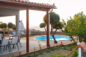 A covered outdoor area with a pool, lounge chairs, and a table.