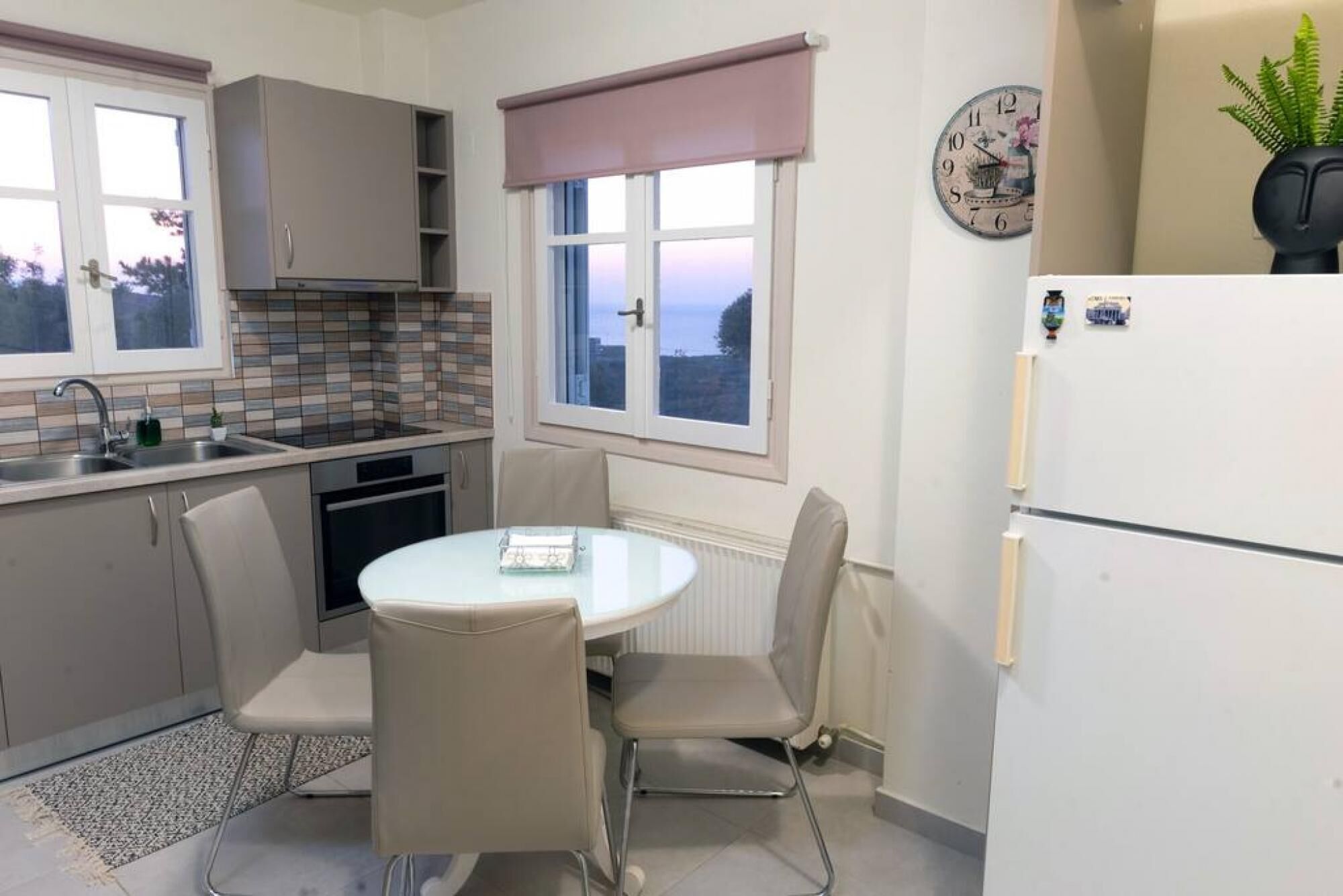 A compact kitchen with a dining table, chairs, a refrigerator, and a window with a view.