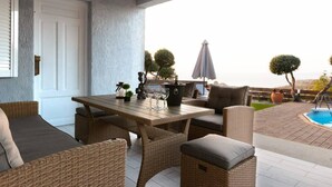 Un espace patio aménagé avec des meubles en osier, une table et une vue sur la mer.