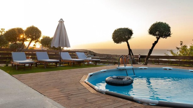 Un espace piscine avec des chaises longues et une vue sur le coucher de soleil.