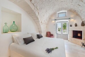 A bedroom with a large bed, a fireplace, and a view of the outdoors.