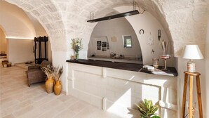 A kitchen with a stone archway, a wooden counter, and a hanging rack. - Masseria Villa Verde (Fasano)