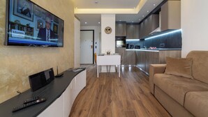 A modern living room with a flat-screen TV, a sofa, and a dining area with a table and chairs. - The Queen Villa Carlotta -21 (Luxembourg)