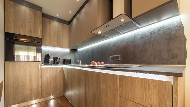 A modern kitchen with wooden cabinetry, a stainless steel range hood, and a built-in oven. - The Queen Villa Carlotta -21 (Luxembourg)