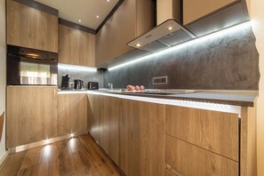 A modern kitchen with wooden cabinetry, a stainless steel range hood, and a built-in oven.