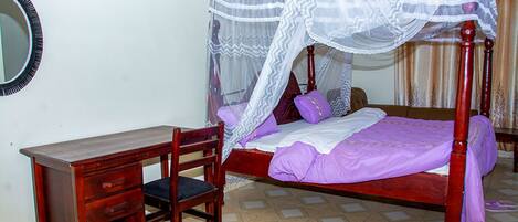 Un dormitorio con cama con dosel, un escritorio de madera y una silla.
