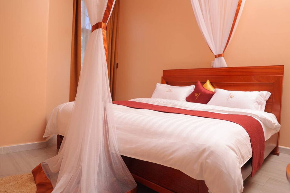 A bedroom with a wooden bed, white bedding, and a red throw blanket.