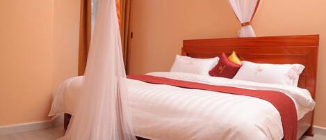 A bedroom with a wooden bed, white bedding, and a red throw blanket.