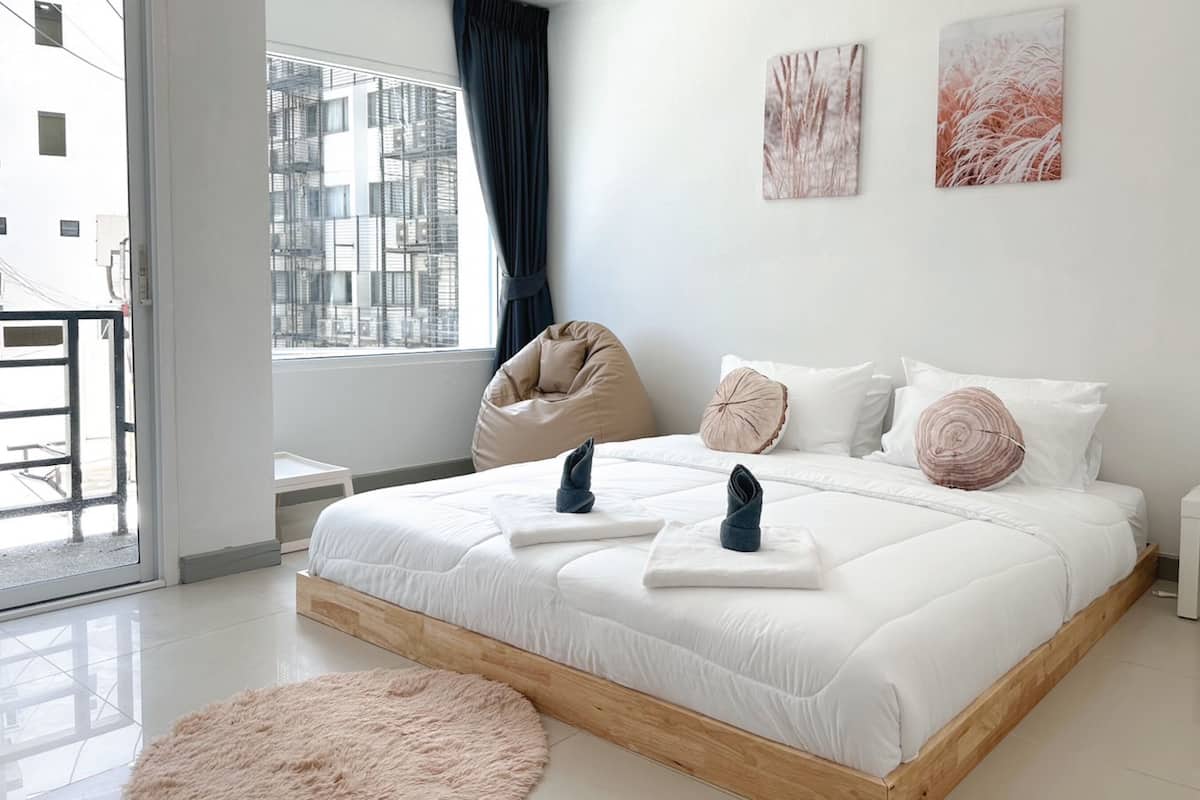 Une chambre moderne avec un grand lit, un fauteuil en forme de poire et des œuvres d’art accrochées au mur.