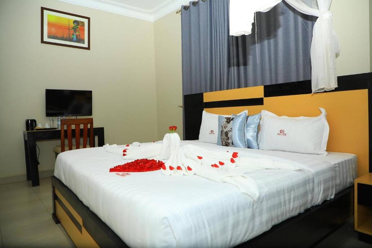 Una habitación de hotel con cama, televisión, escritorio y un cuadro en la pared.