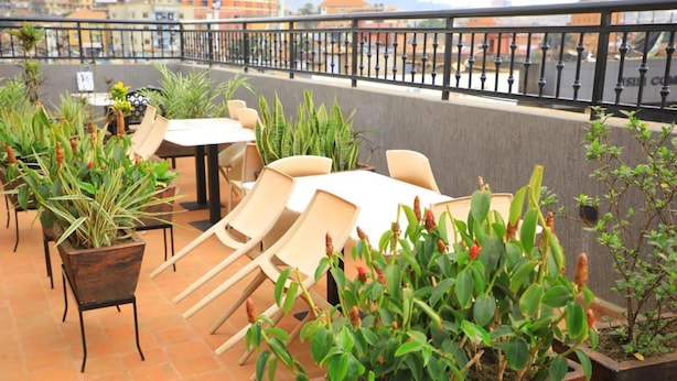 Una terraza en la azotea con mobiliario exterior y plantas en macetas.
