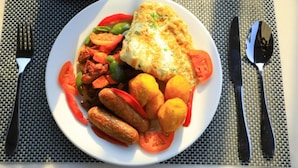 Un plato de comida con pescado, verduras y salchichas.