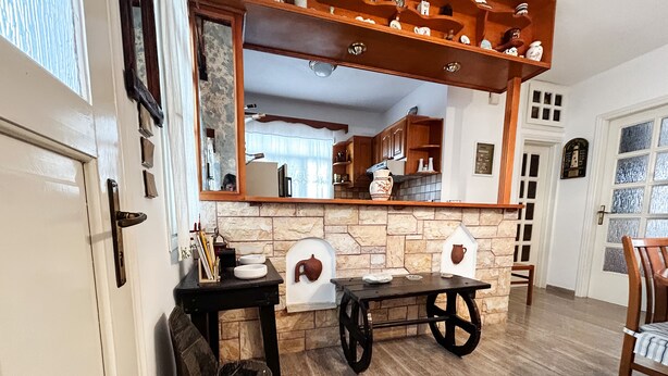 Une cuisine avec un mur recouvert de pierres apparentes, des armoires en bois et une petite table avec des chaises.