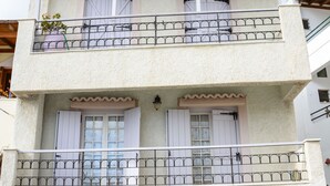 Un bâtiment à deux étages, doté d’un balcon à l’étage supérieur, d’une petite fenêtre au rez-de-chaussée et d’un panneau indiquant qu’il est interdit de se garer.