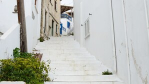 Un escalier blanc mène vers le haut d’une rue étroite, bordée de bâtiments blancs rehaussés de touches de bleu.