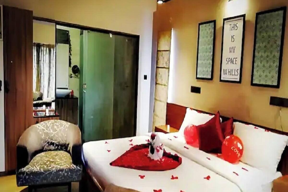 A hotel room with a bed, a chair, a desk, and a sliding door.