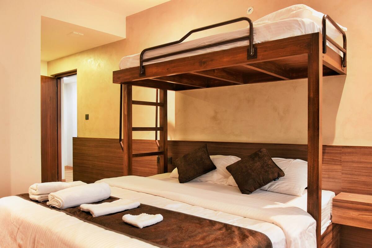 A bunk bed with a wooden frame, white bedding, and a brown headboard.