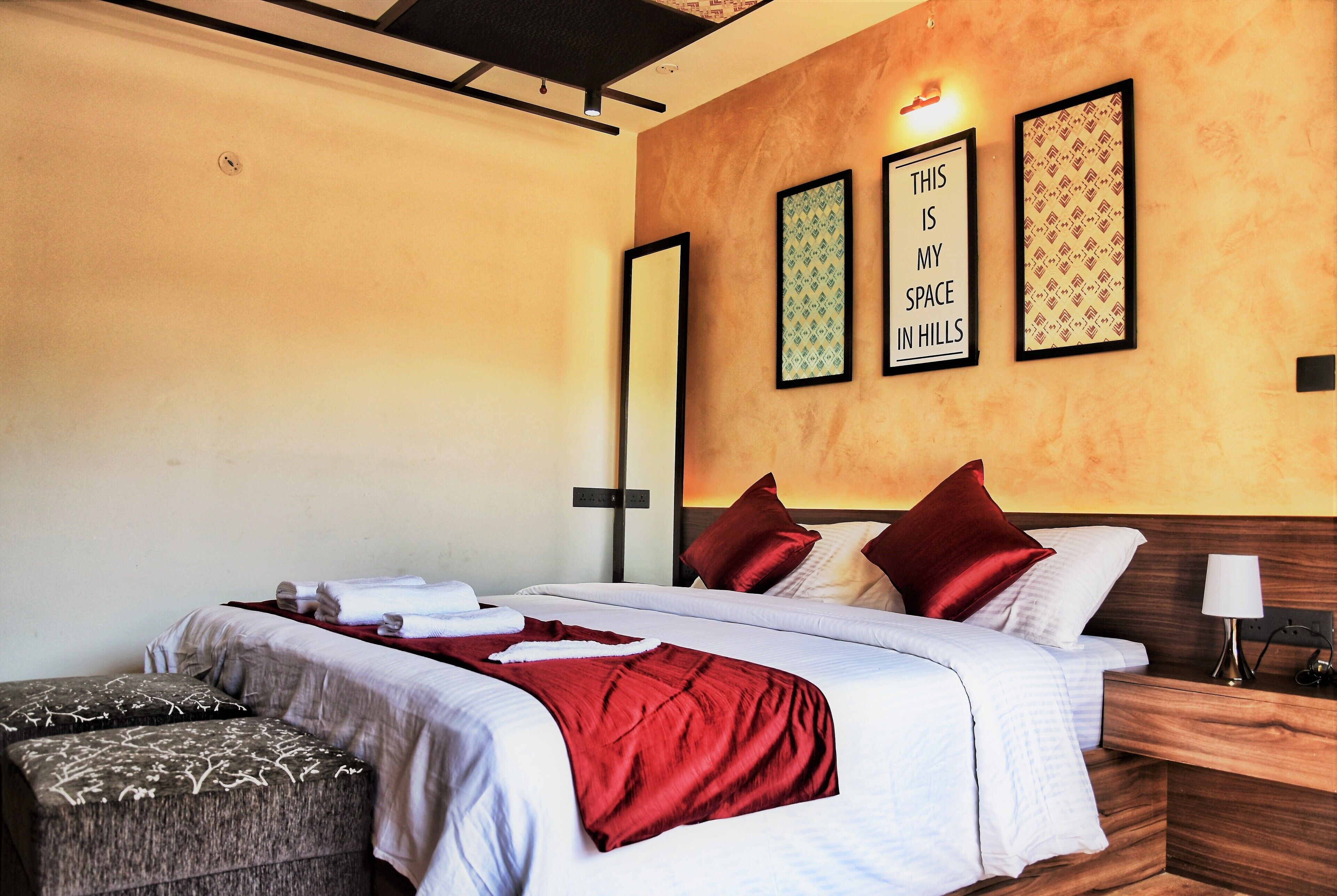 A hotel room with a bed, a nightstand, a lamp, and wall art.