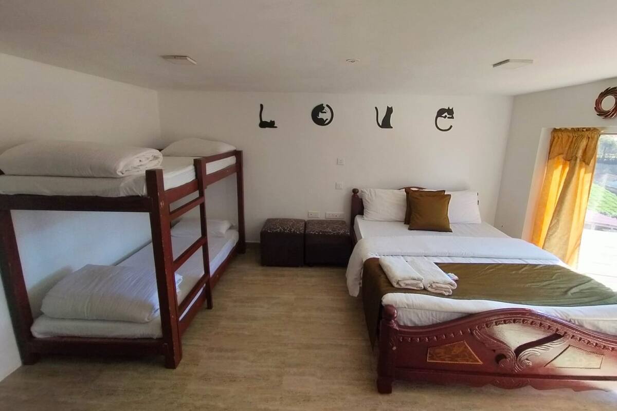 A room with bunk beds, a single bed, and a small table.