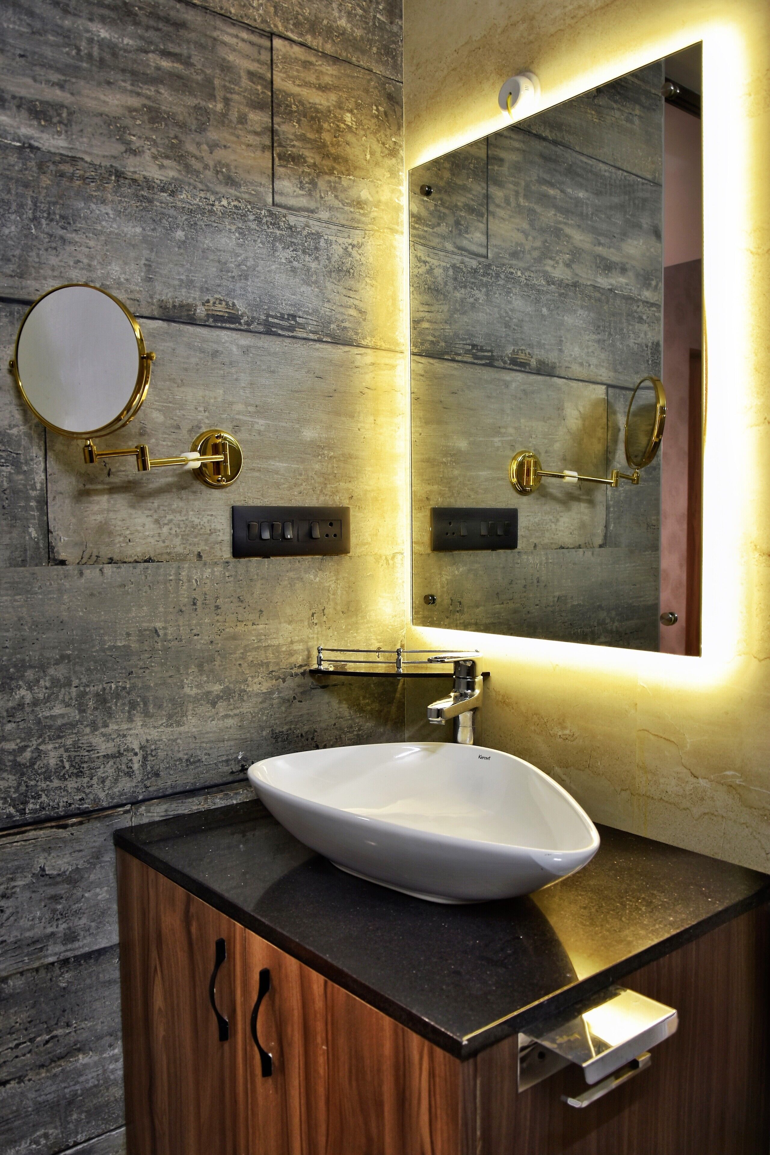 Une salle de bain avec un meuble-lavabo en bois, un lavabo blanc et un miroir avec un cadre doré.