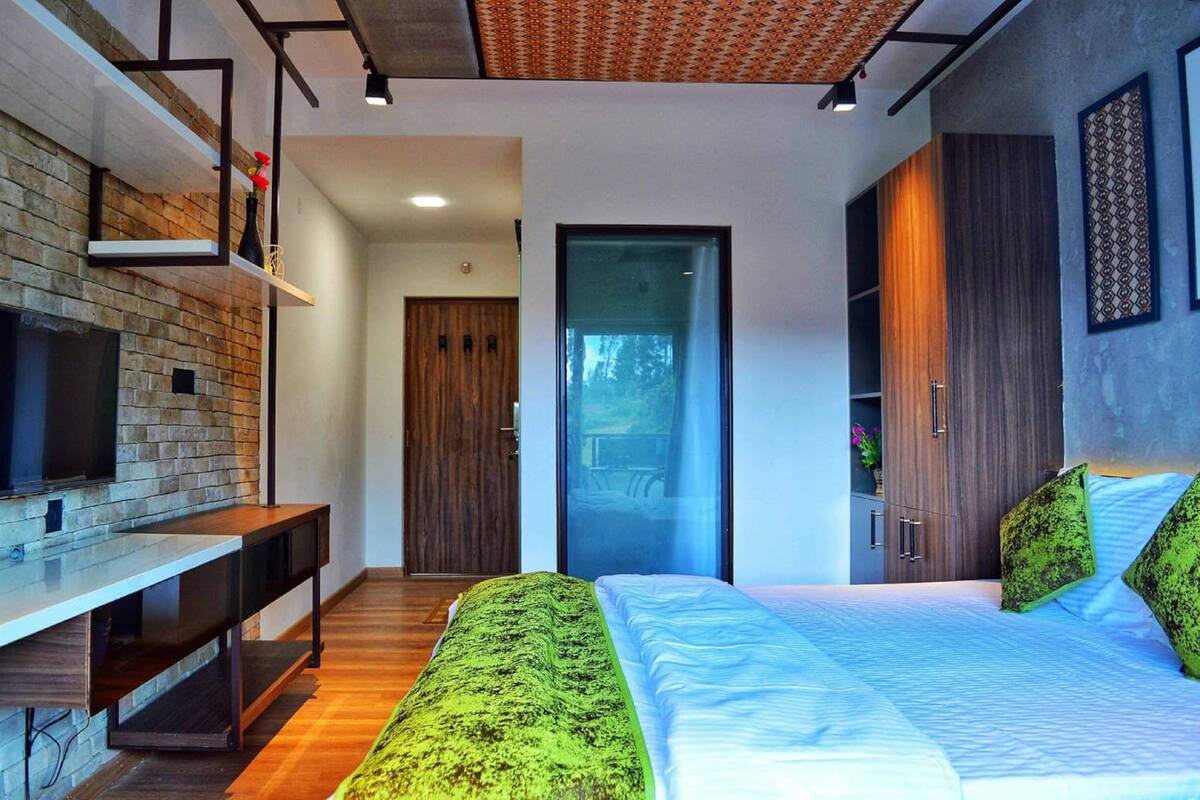 A modern bedroom with a bed, a TV on a built-in shelf, and a wardrobe.