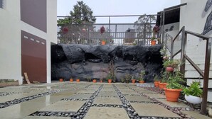 Une cour avec un chemin en pierre, des plantes en pot et un mur de pierres.