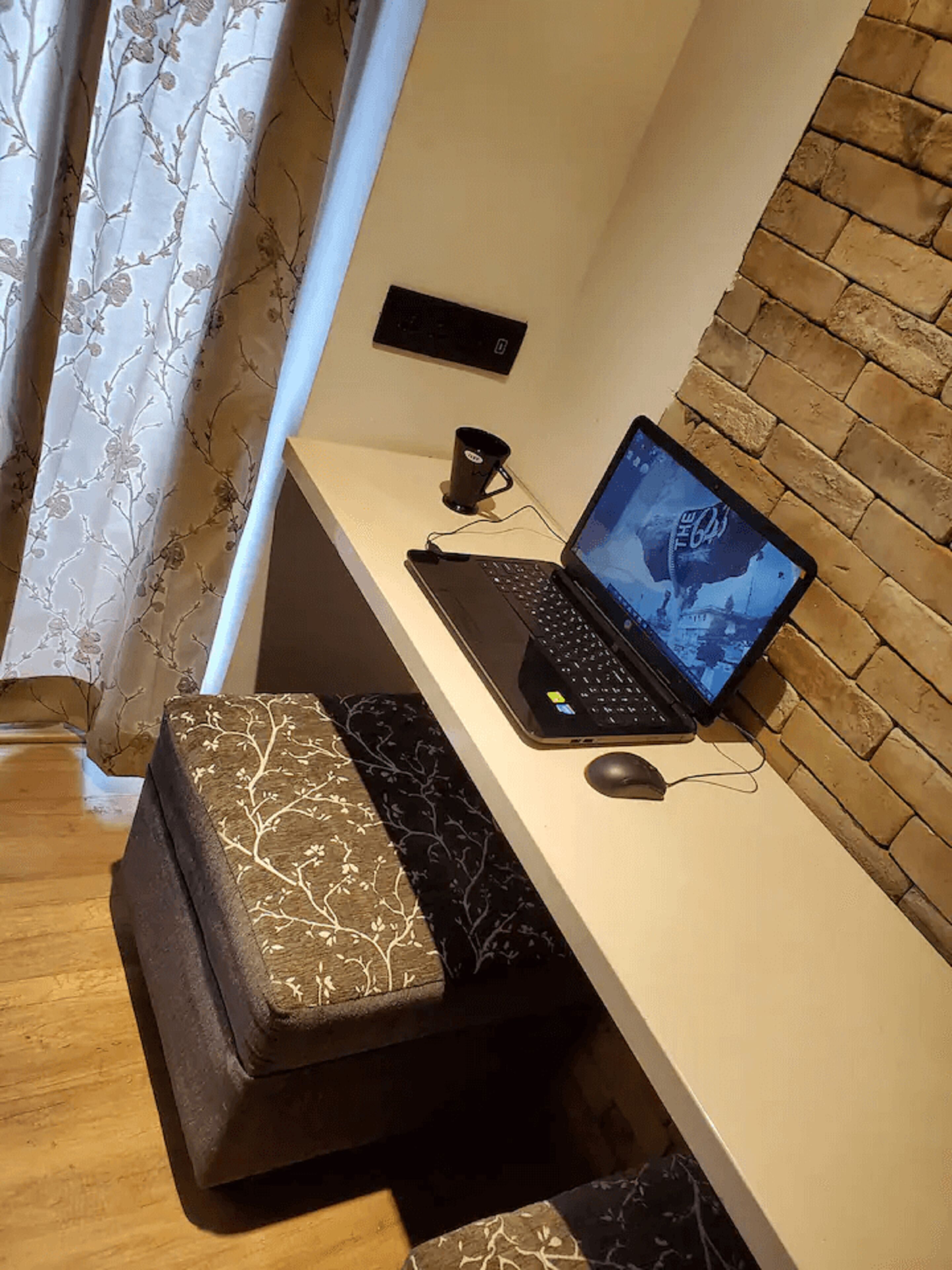 Un ordinateur portable sur un bureau, avec une souris, une tasse et une prise électrique.