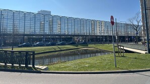 Un bâtiment moderne doté d’une façade en verre, d’un petit étang et d’une promenade piétonne.