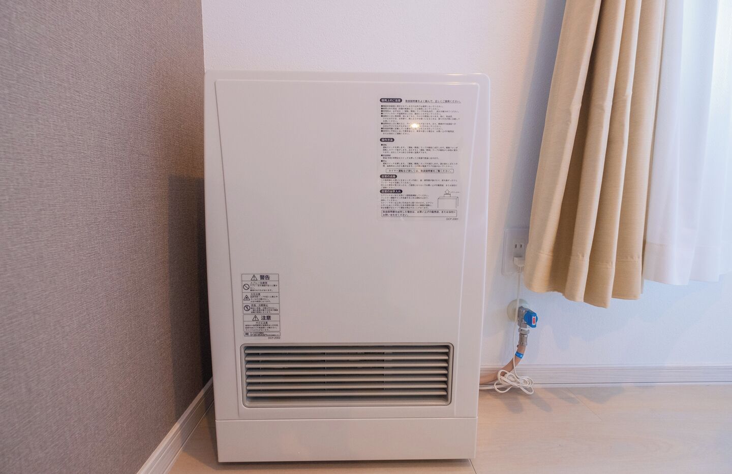 Calentador portátil blanco con rejilla de ventilación, cable de alimentación y una etiqueta con texto.