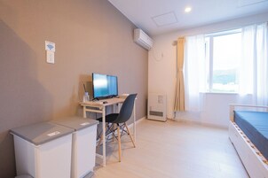 A compact hotel room with a desk, chair, and a bed.