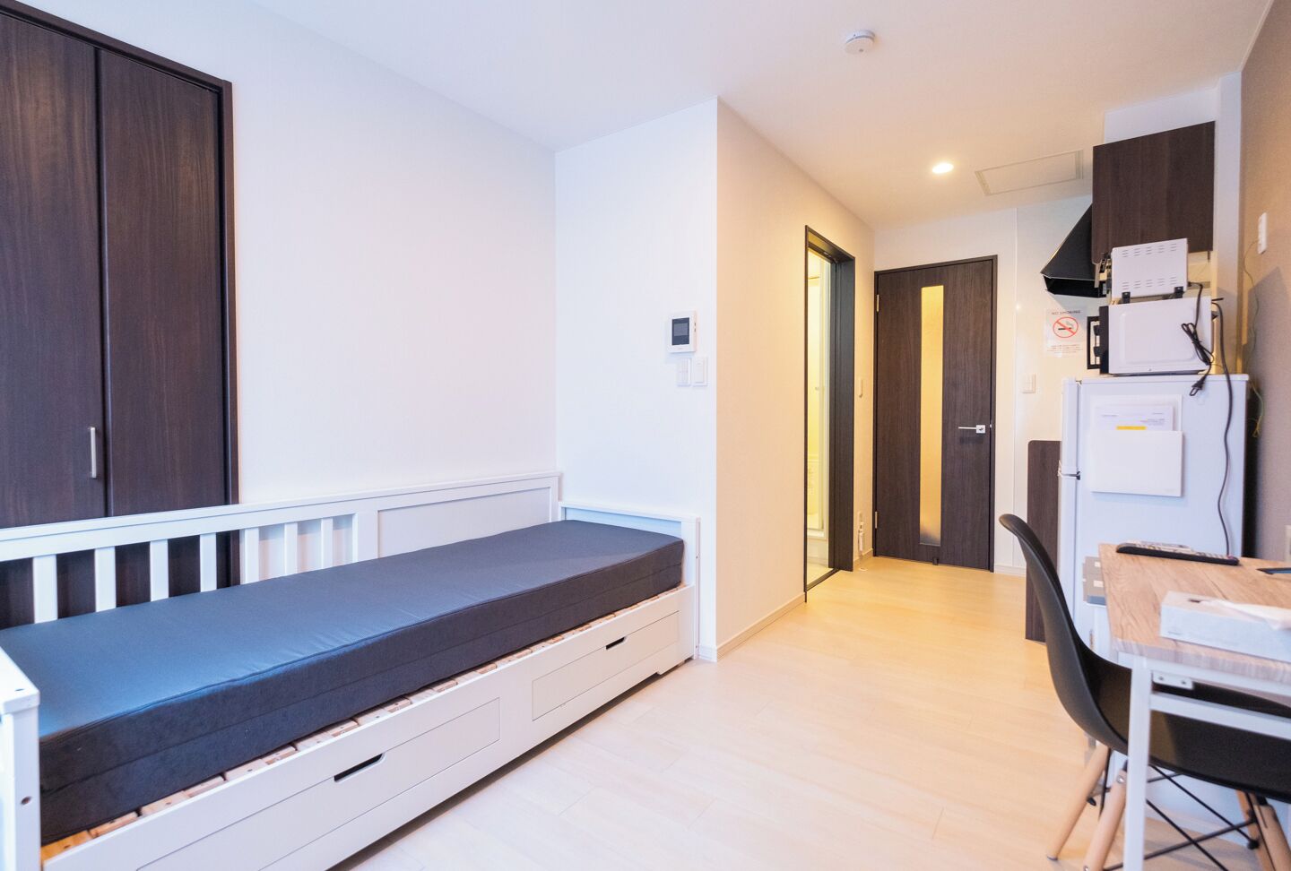 Una habitación compacta con una cama, un escritorio pequeño y una zona de kitchenette.