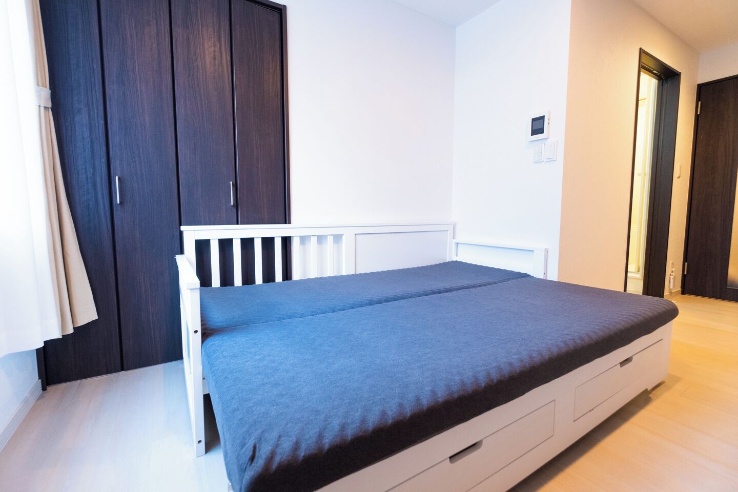 Quarto com uma cama de solteiro, um guarda-roupa escuro e um radiador branco.