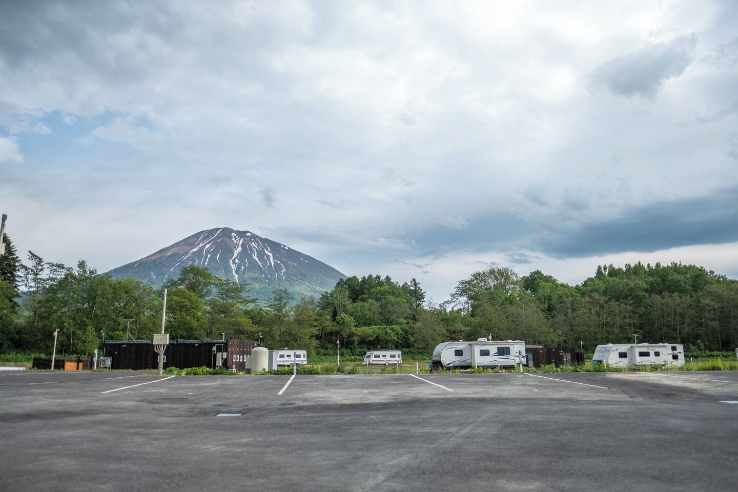 Un estacionamiento con vehículos recreativos y una montaña al fondo.