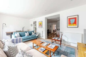 A modern living room with a blue sofa, a wooden coffee table, and a patterned rug.