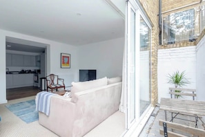 Relax in this stylish living space with a comfortable sofa, kitchen access, and a balcony or patio just steps away.