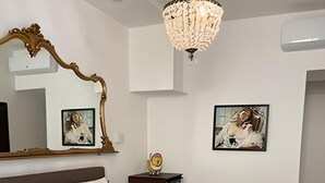 Un dormitori amb un llit gran, una làmpada penjant, un mirall i dos quadres a la paret.