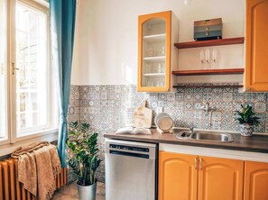 A kitchen with a dishwasher, a sink, and a cabinet with glass doors. - TurnKey | City Mall Studio (Praha)