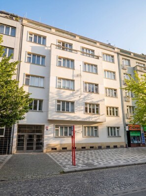 A multi-story building with a flat facade, large windows, and a ground-level entrance with a metal gate.