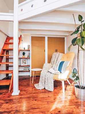 A cozy room with a wooden floor, a chair with a cushion, a small table, and a potted plant. - TurnKey | City Mall Studio (Praha)