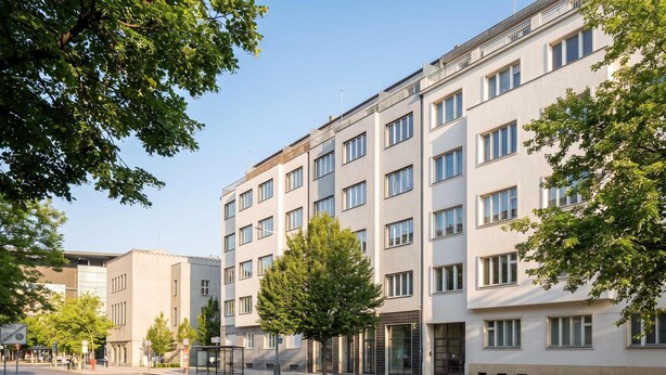 Ein mehrstöckiges Gebäude im modernen Architekturstil, mit einer Reihe von Fenstern und Balkonen.