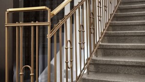 A staircase with a metal handrail and glass railings.