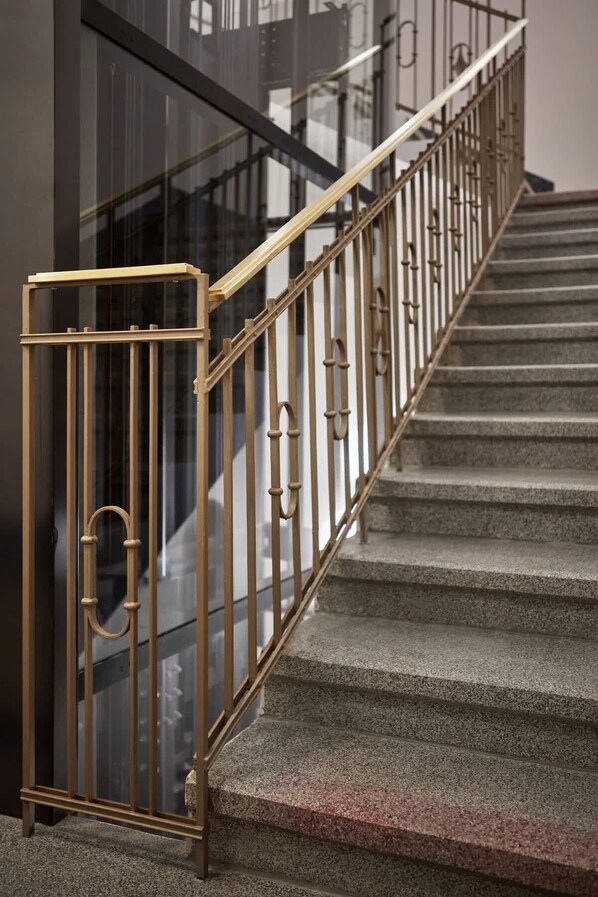 Una escalera con barandilla de metal y balaustradas de vidrio.